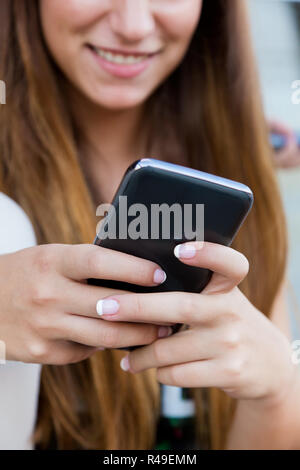 Beautiful girl having fun with smartphone after class. Stock Photo