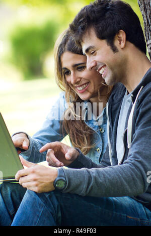 Portrait of young couple at the park using a laptop Stock Photo