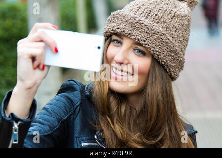 Cute brunette woman taking photo of herself on the street Stock Photo