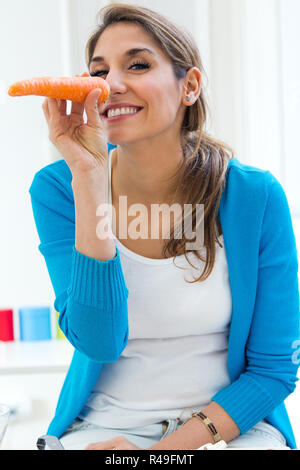 pretty young woman having fun with a carrot in the kitchen Stock Photo