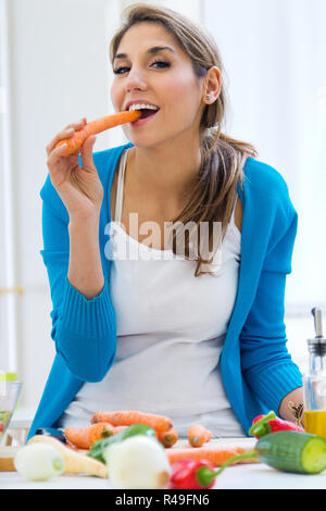 pretty young woman having fun with a carrot in the kitchen Stock Photo