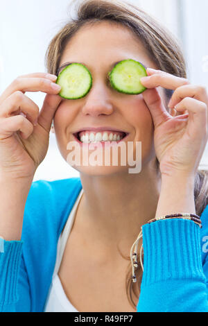 pretty young woman having fun with a cucumber in the kitchen Stock Photo