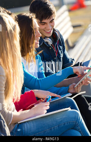 Students having fun with smartphones and tablets after class Stock Photo