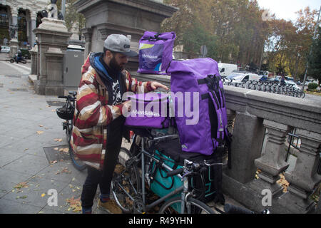 Madrid, Spain. 26th Nov, 2018. Bicycle dealer seen showing pedestrians their work tools during the protest.Hundreds of delivery people on bicycles from different companies such as Uber Eats, Glovo or Deliveroo, have met in Madrid to protest and to inform people about their situation. The distributors in bicycles of these companies denounce the labor precariousness in their sector and distributors of all the Spanish cities after the two days reunited in the assembly and decided to create an association to demand for their labor situation with the company must be recognized and they should Stock Photo