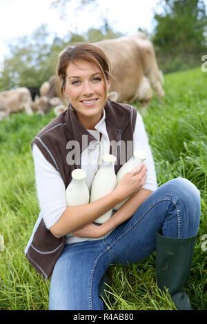 Smiling breeder woman holding bottles of milk