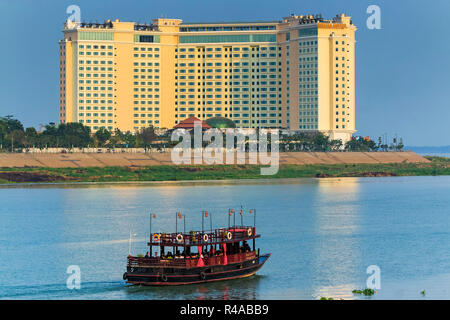 Sunset cruise boat & Sokha hotel at the confluence of the Tonle Sap & Mekong rivers; central riverfront, Phnom Penh, Cambodia Stock Photo