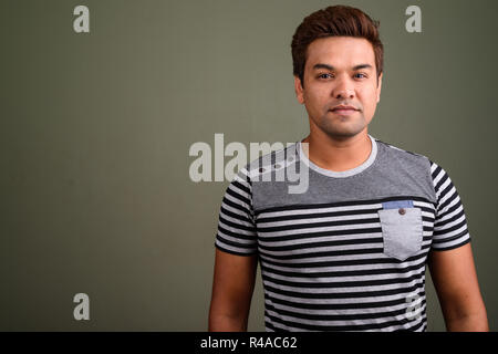 Indian man wearing striped shirt against colored background Stock Photo