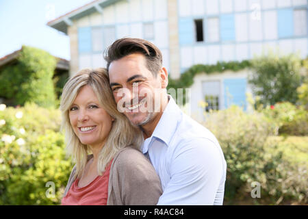 Cheerful mature couple standing in front of house Stock Photo