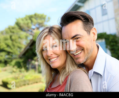 Cheerful mature couple standing in front of house Stock Photo