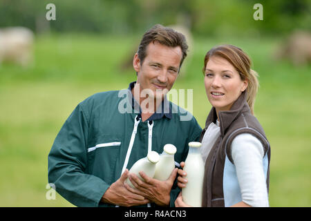 Couple of farmers in field holding milk bottles Stock Photo
