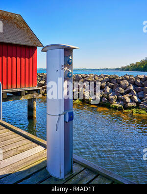Charging station for boats, sockets for loading ships in the port. Bollard point of electrical outlets on pier at the Baltic Sea. Stock Photo