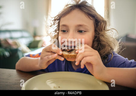 Cute little boy eating lunch at his dining room table  Stock Photo