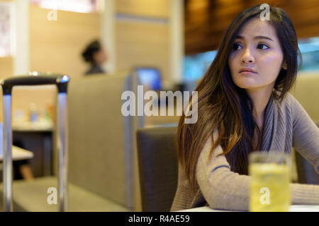 Young beautiful Asian woman sitting inside the restaurant