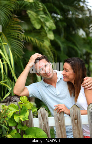 Couple leaning on fence in front of home Stock Photo