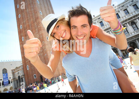 Man giving piggyback ride to girlfriend in San Marco Place, Venice Stock Photo
