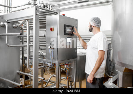 Worker operating pasteurizer using the control panel at the cheese or milk manufacturing Stock Photo