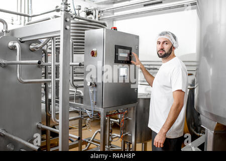 Worker operating pasteurizer using the control panel at the cheese or milk manufacturing Stock Photo