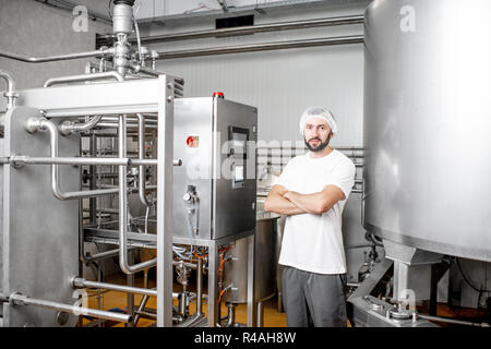 Portrait of a handsome worker operating pasteurizer using the control panel at the cheese or milk manufacturing Stock Photo
