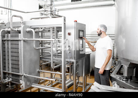 Worker operating pasteurizer using the control panel at the cheese or milk manufacturing Stock Photo