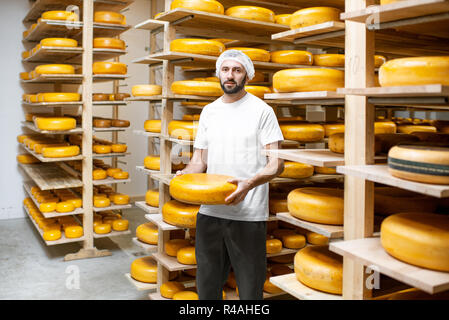 Cheese maker showing cheese wheel at the cheese storage Stock Photo - Alamy