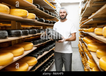 Cheese maker showing cheese wheel at the cheese storage Stock Photo - Alamy