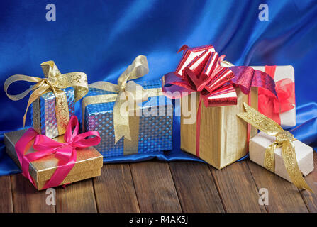 Gift boxes with ribbons on wooden table and blue silk Stock Photo