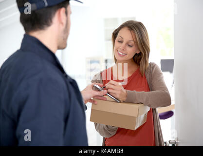 Woman sigining electronic receipt of delivered package Stock Photo