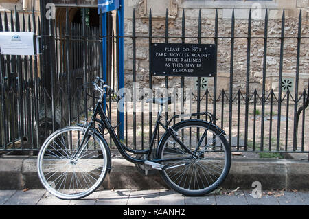 Around the UK- Bicycle leant against 'no parking' sign on railings Stock Photo