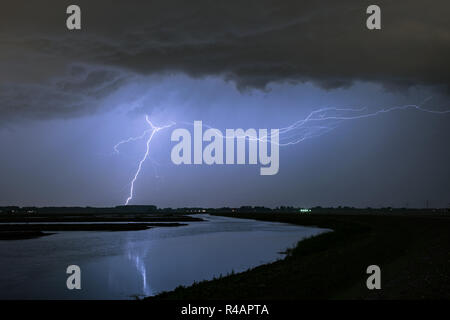 Horizontal and vertical lightning bolts from a severe thunderstorm over a lake in the western part of Holland Stock Photo