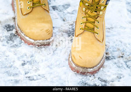 Yellow working boots from nubuck in the snow footpath. Winter footwear background Stock Photo