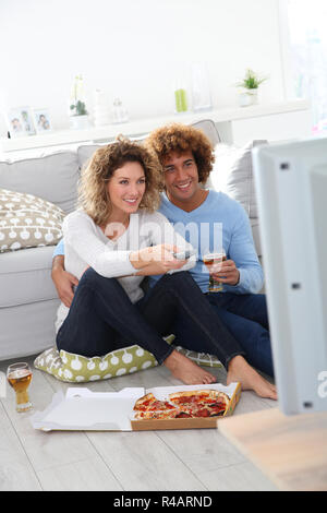 Cheerful couple at home having pizza in font of TV Stock Photo
