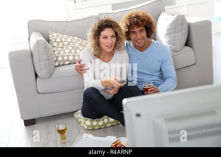 Cheerful couple at home having pizza in font of TV Stock Photo