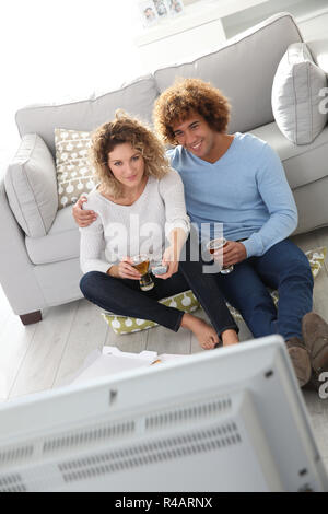 Cheerful couple at home having pizza in font of TV Stock Photo