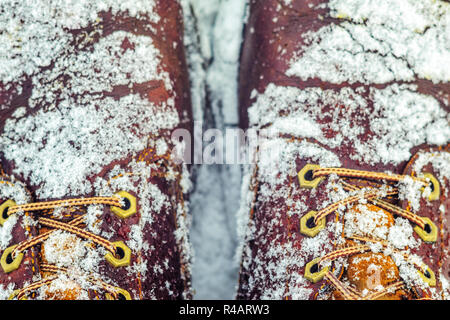 First person view of legs in brown boots in the snow. Snow on boots while walking in winter. Footwear background Stock Photo