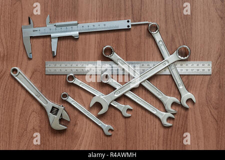 Set of wrenches, caliper, ruler and adjustable wrench on a wooden table. View from above Stock Photo