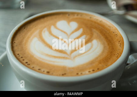 Close up of cup of cappuccino with beautiful latte art on a grey wooden table in a cafe. Stock Photo