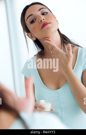 Young woman caring of her skin standing near mirror in the bathroom. Stock Photo
