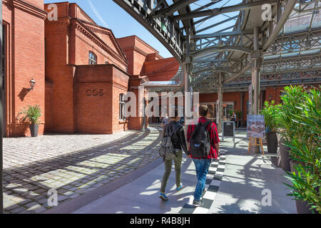 Shopping centre center, rear view of young people walking towards the entrance to a shopping mall - the Stary Browar - in the city of Poznan, Poland. Stock Photo