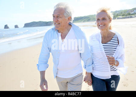 Senior couple running on a sandy beach Stock Photo