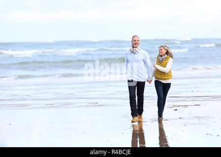 Senior couple running on the beach in winter time Stock Photo