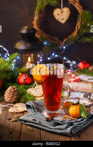 Merry Christmas gift card concept with hot mulled wine, tangerines or oranges and spices. Lantern, Christmas tree, balls and lights in the background. Stock Photo