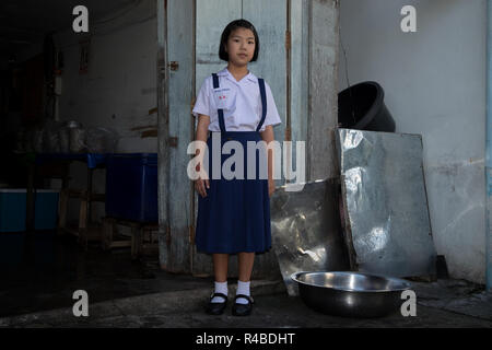 A schoolgirl poses outside a food shop in Hat Yai, Thailand. Stock Photo