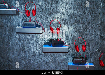 red headphones near to glasses for virtual reality on the background of a wooden gray wall Stock Photo