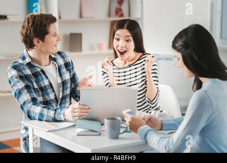 Job of dreams. Dark-haired student feeling extremely surprised after getting job of her dreams Stock Photo