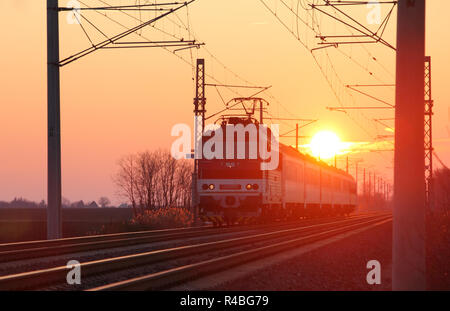 Passenger train on railway at sunset Stock Photo