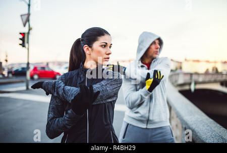 A fit couple runners doing stretching outdoors on the bridge in Prague city. Stock Photo