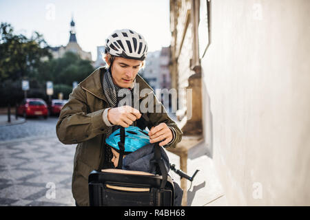A small toddler boy sitting in bicycle seat with father outdoors in city. Stock Photo