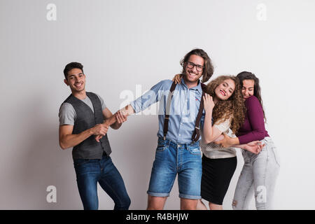 Portrait of young group of friends standing in a studio, having fun. Stock Photo
