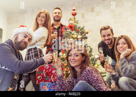 Happy and smiling friends toast under the christmas tree Stock Photo