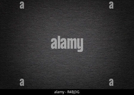 Texture of vintage dark black paper background with vignette. Structure of dense gray kraft cardboard with frame. Felt gradient backdrop closeup. Stock Photo